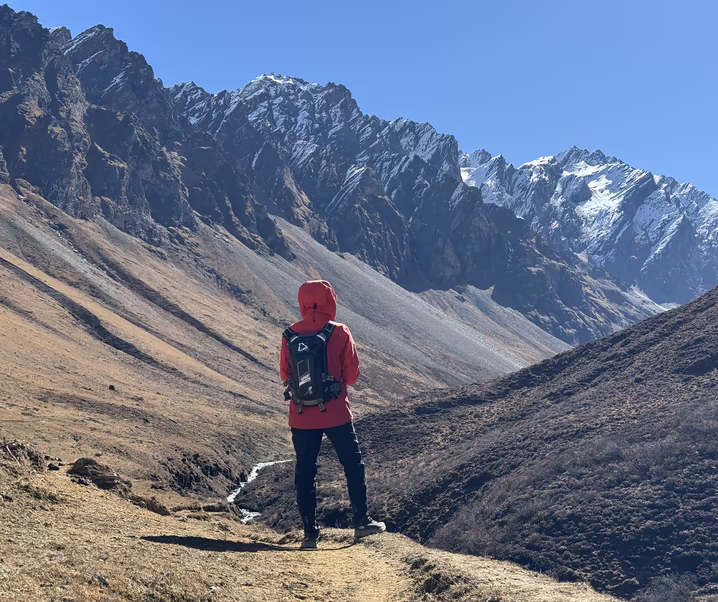 A trekker facing snow-capped mountains on the Soi Yaksa trail in Bhutan